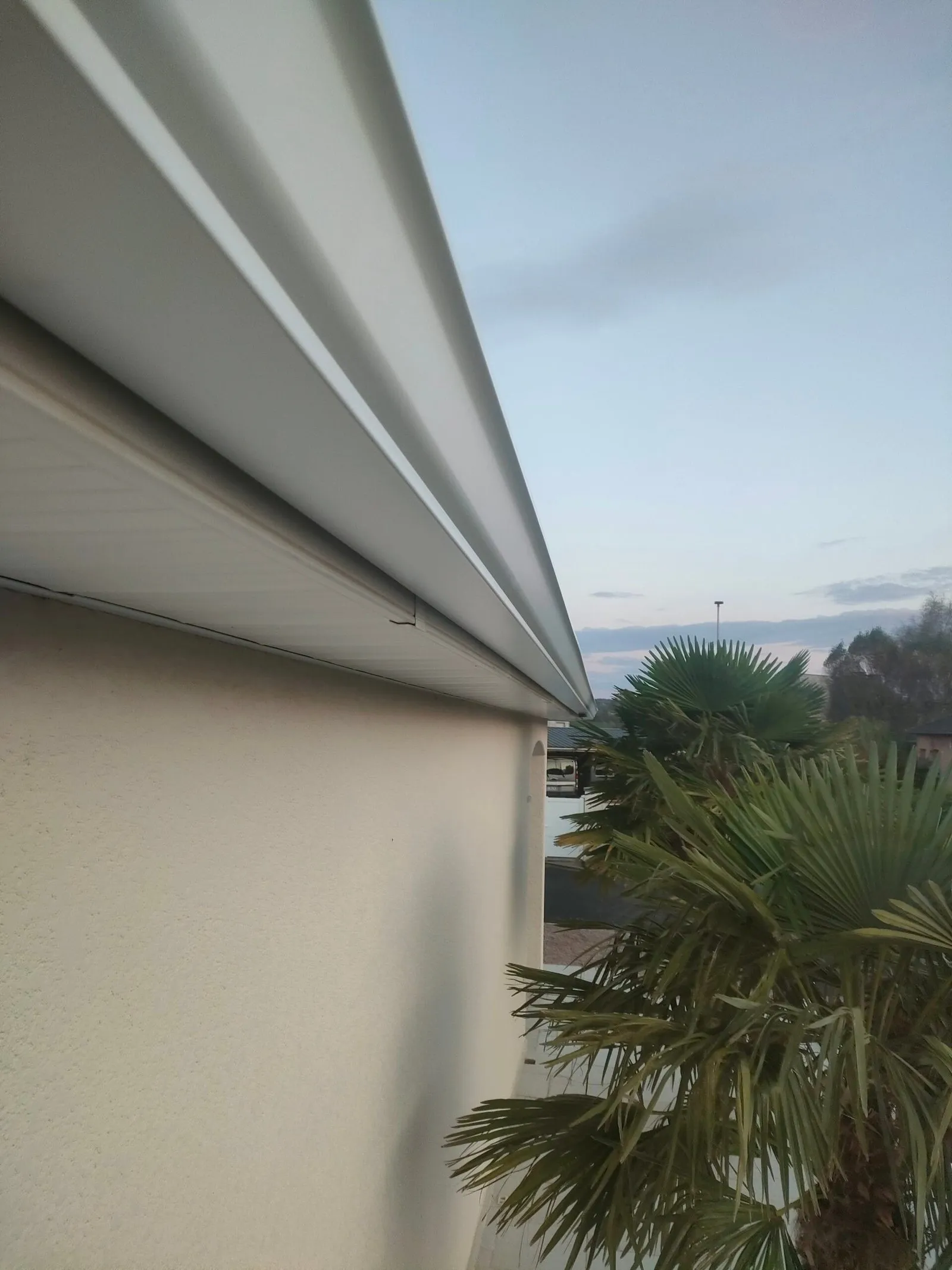 Gouttière en aluminium blanche installée en bord de toiture d'une maison.