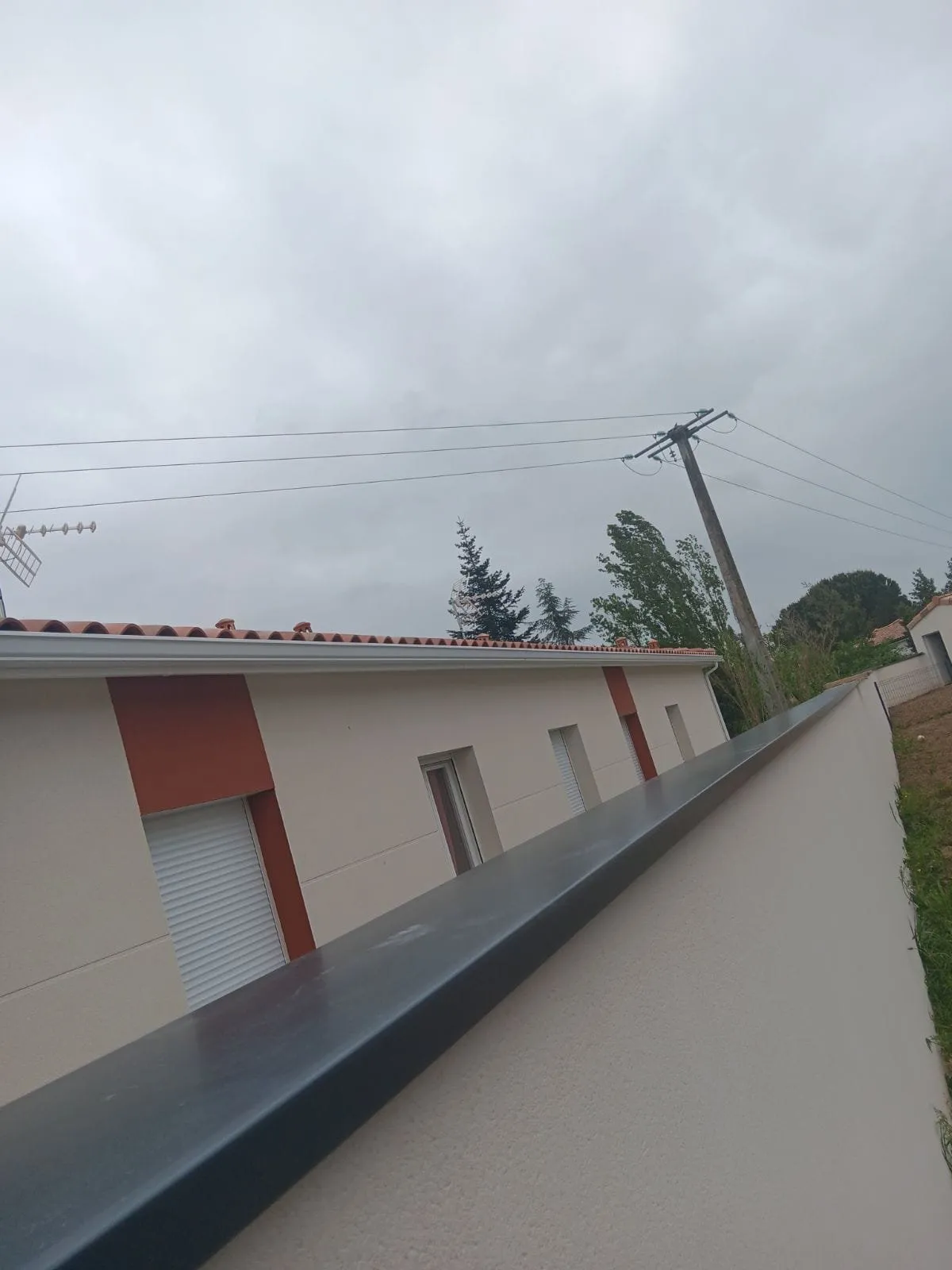 Couvertine métallique gris foncé posée sur le mur extérieur d'une maison.